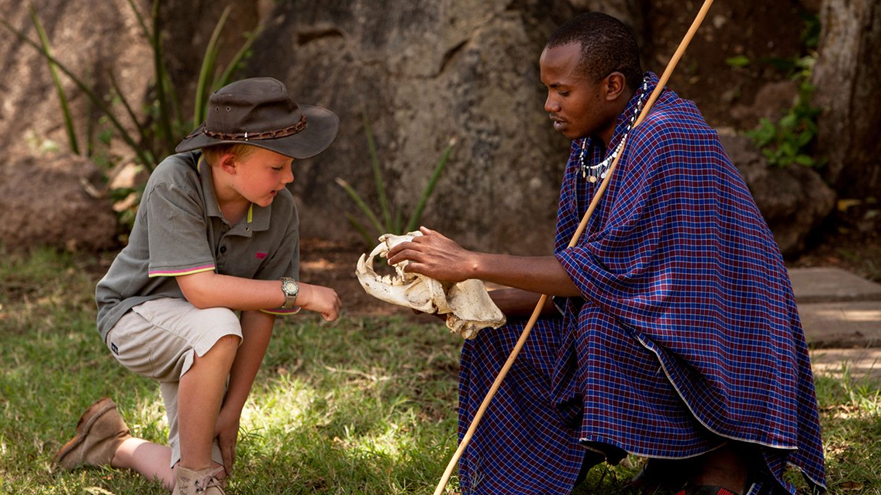 A Maasi guide at the Lodge helps a child—Serengeti, Africa
