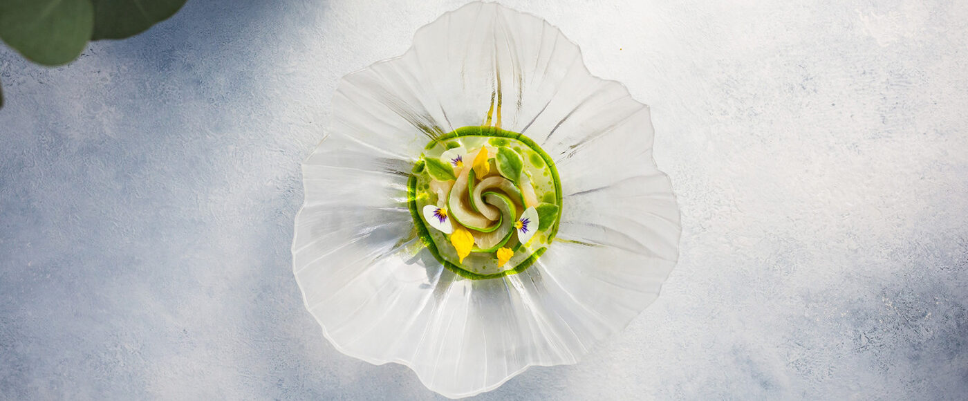 Green and yellow dish plated on an organic-edged glass plate