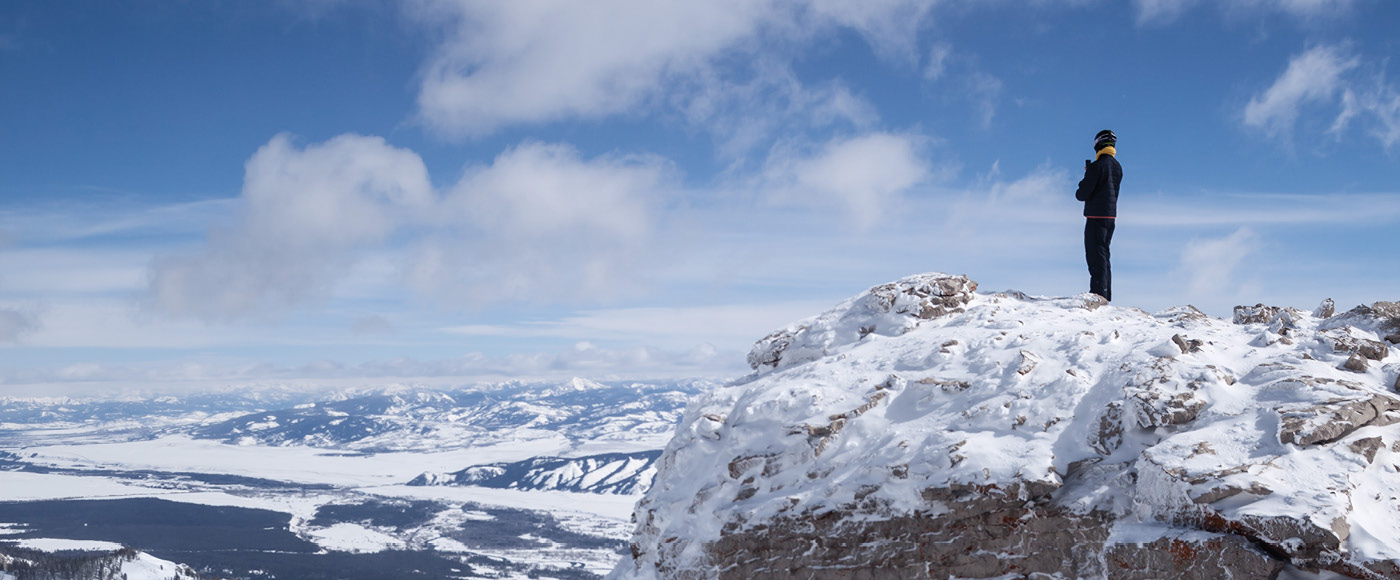 Person standing at the top of a snowy mountain