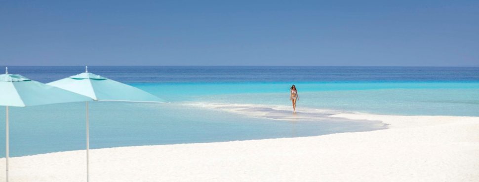 Two umbrellas on beach with turquoise water