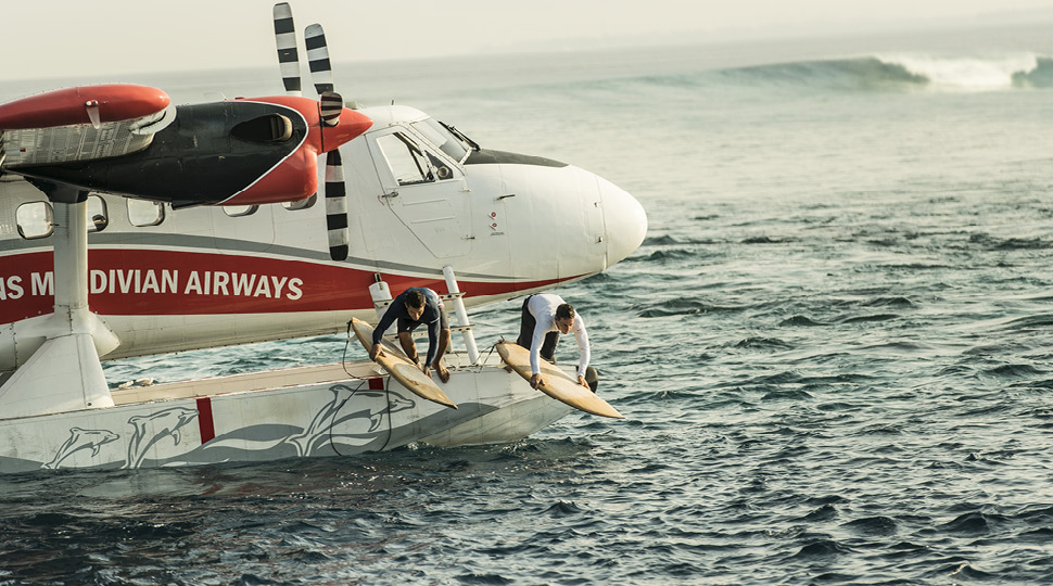 Two surfers dive off of a seaplane into the ocean