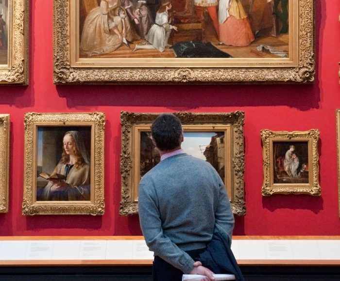Man looks at paintings in the Victoria and Albert Museum, London, England, UK.