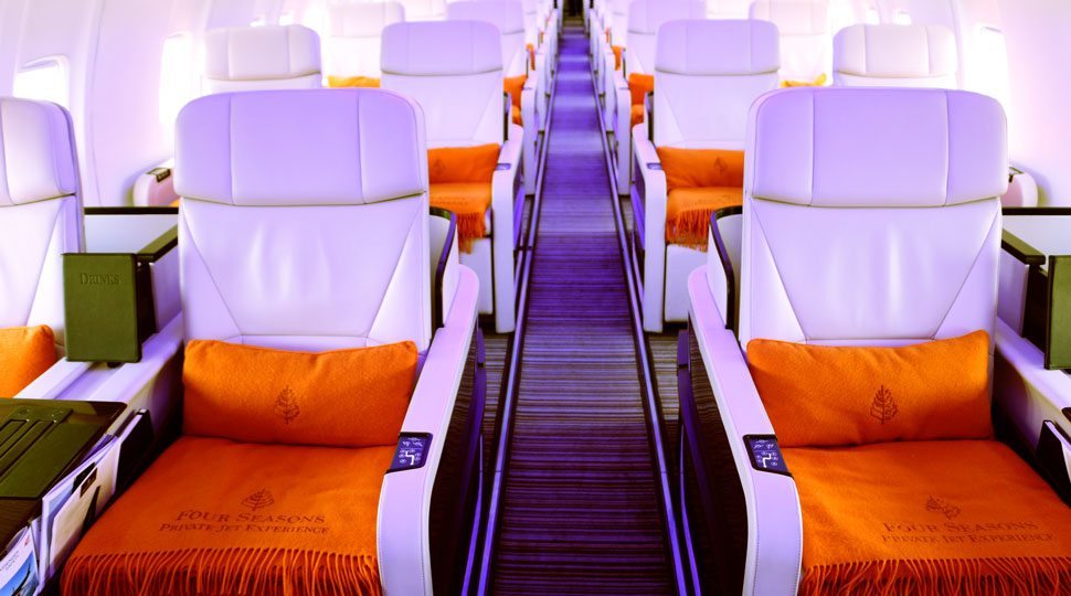 An empty jet chairs with orange pillows and blankets