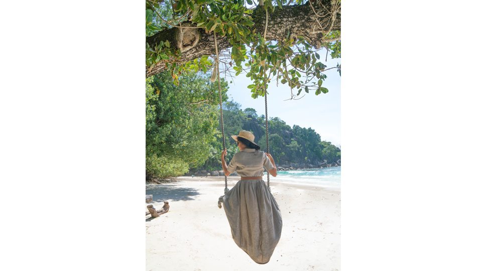 Blogger Marcy Yu swings on a beach at the Four Seasons Seychelles