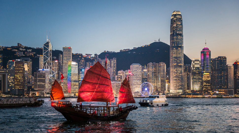 A junk boat sails past the Hong Kong skyline
