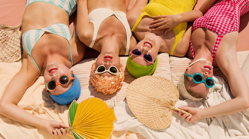 Four women sunbathing with fans