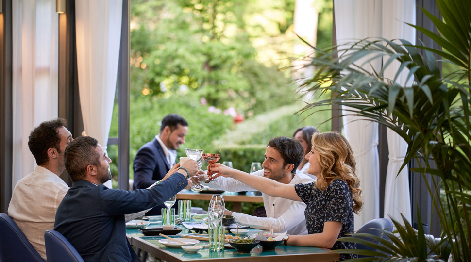 Group of four people toast their glasses at a dining table