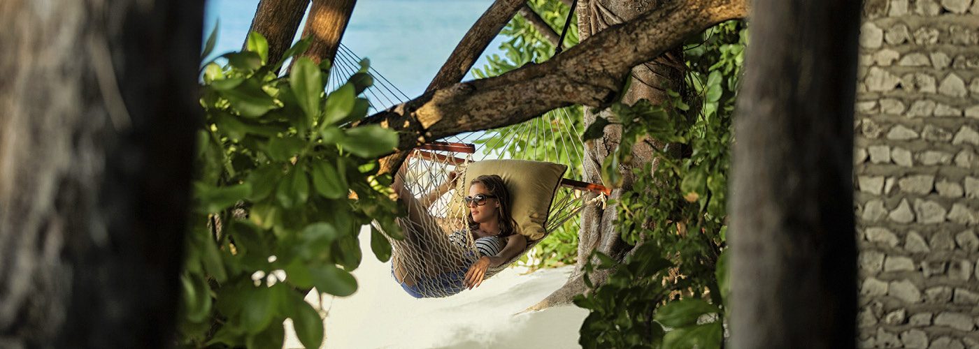Woman lounges in a beachside hammock