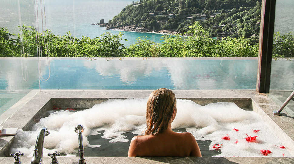 A woman sitting in a bubble bath with rose petals