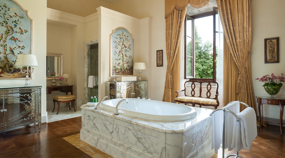 A spacious, ornate bathroom with a raised marble bathtub in the center