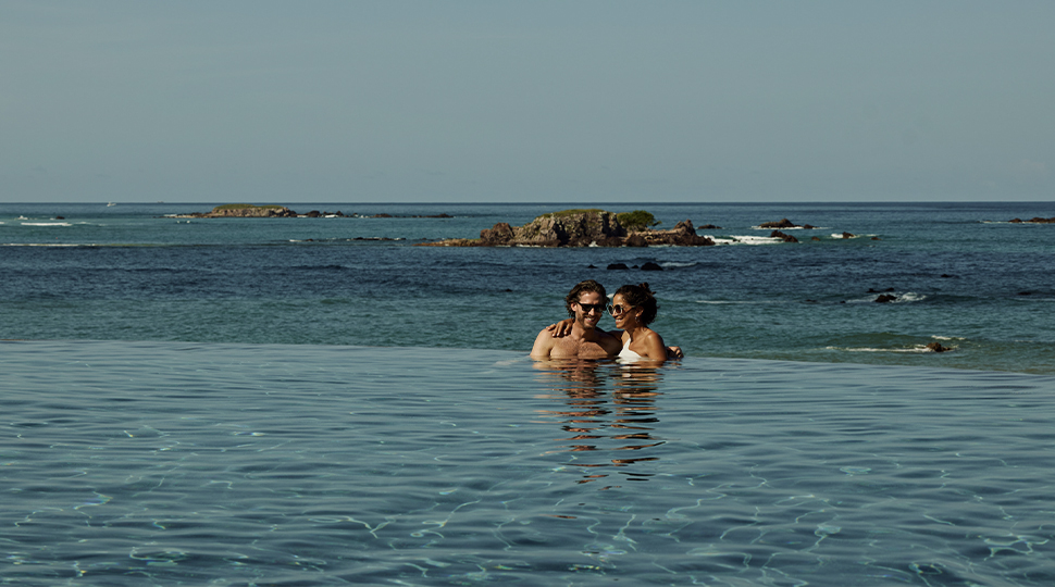 A couple lounging in an infinity edge by the ocean