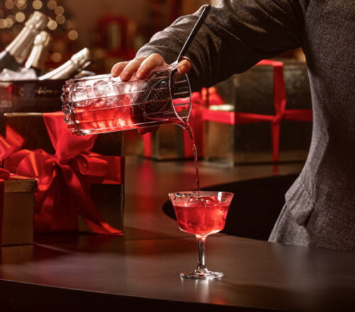 A mixologist pours a red holiday cocktail