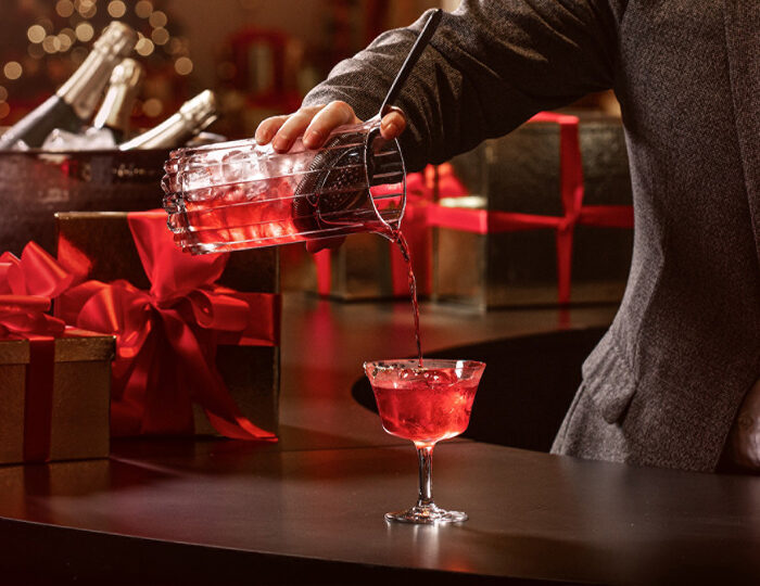 A mixologist pours a red holiday cocktail