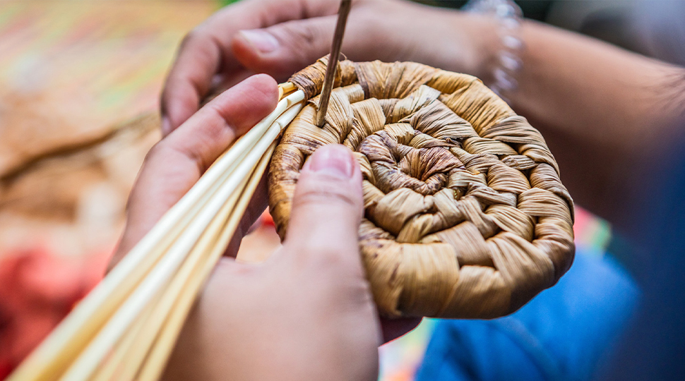 Close up of a woman's hands weaving a basket