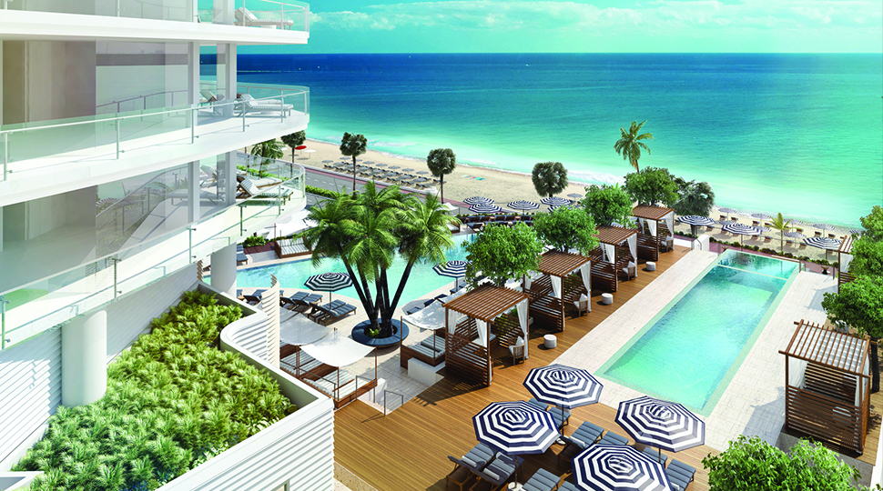 Overhead view of two pools, striped umbrellas, lounge chairs, palm trees and the beach and ocean in the distance