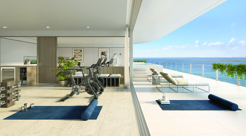 Navy yoga mats, stationary bicycle and lounge chairs on a covered terrace overlooking the ocean