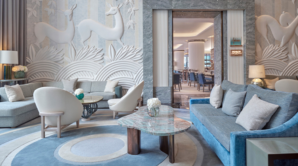 Lounge area with white and blue furnishings and white walls featuring textured images of deer and plants