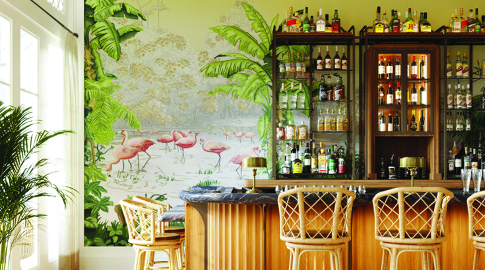 Bar area with rattan stools and counter, large wood-and-glass cabinet and a tropical mural on the wall
