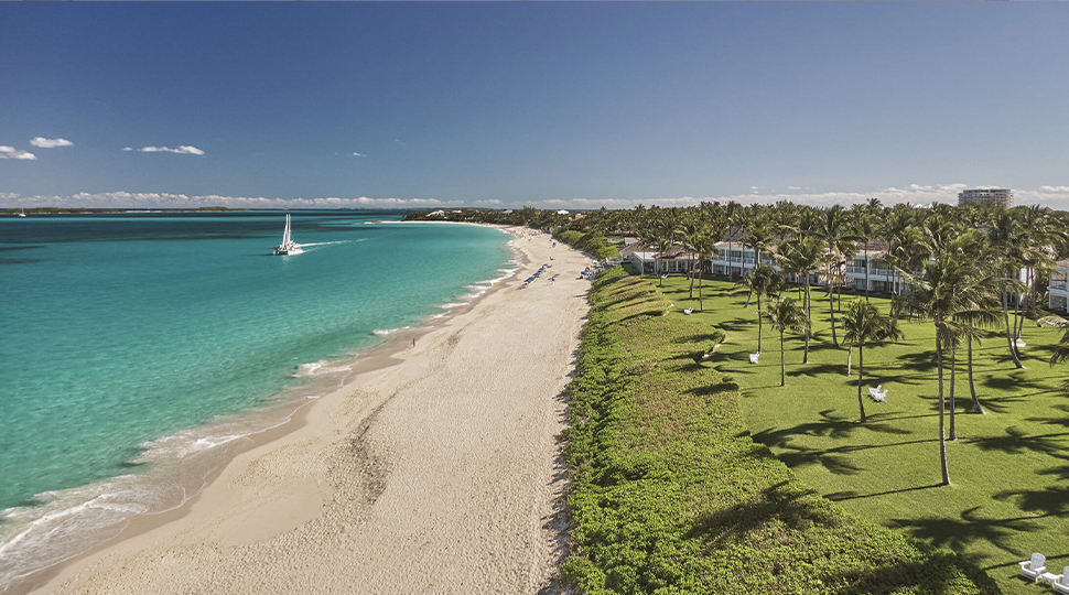 Aerial view of a beach with the ocean on one side and a manicured lawn on the other