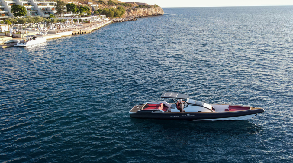 A red, white and black speedboat cruises on the water off the coastline of Athens