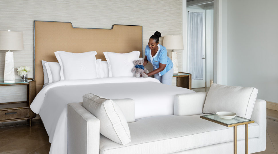 Housekeeping person puts finishing touches on a bed