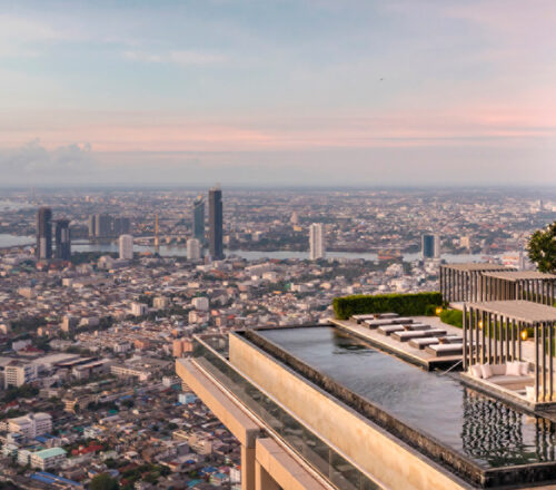 Rooftop pool sits on top of a skyscraper overlooking the city with a large Four Seasons tree logo next to it