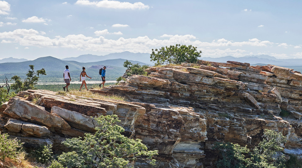 Three people hike through a rugged, rocky hillside