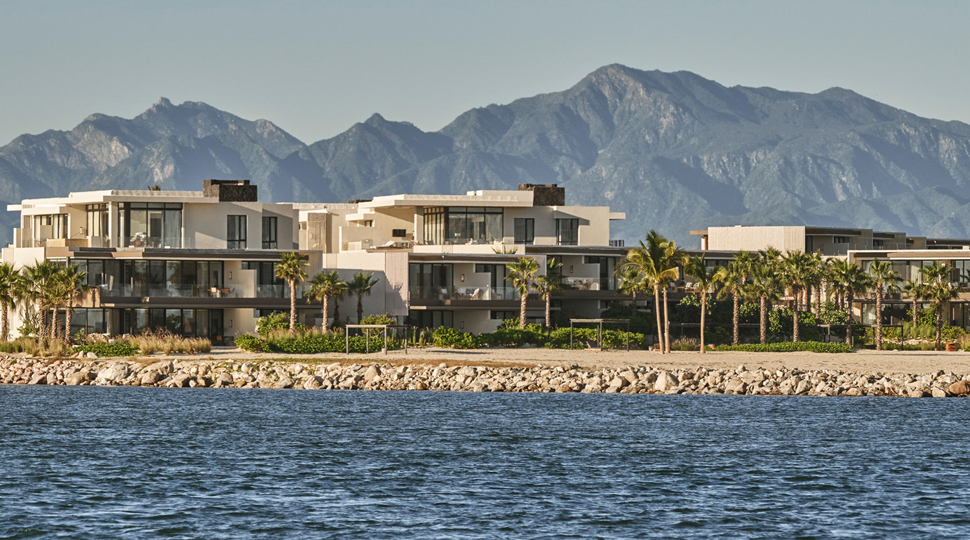 Oceanfront resort sits between the water and a row of mountains in the background