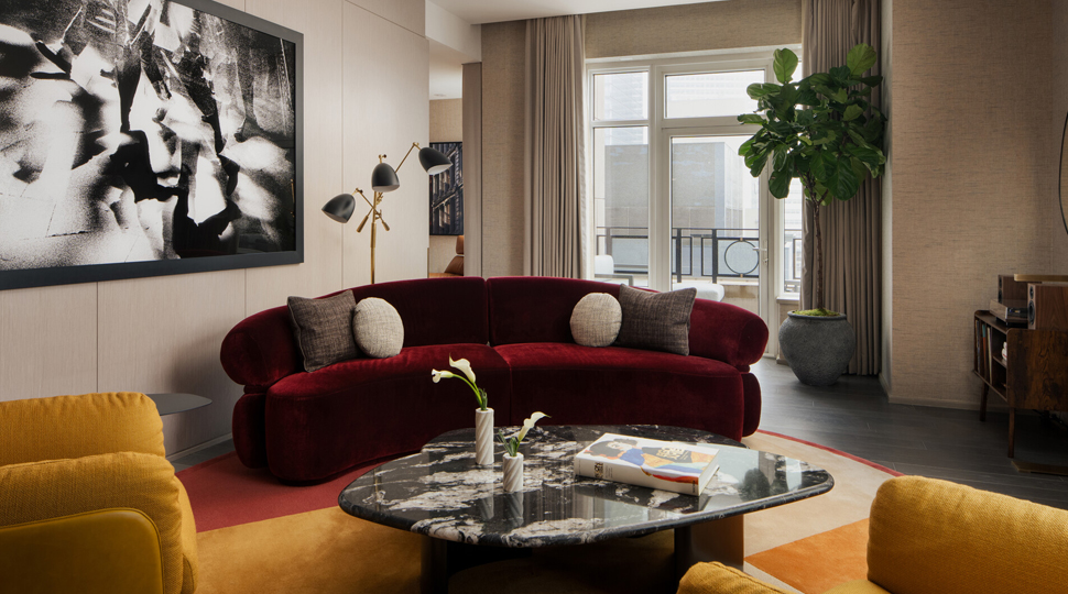 Burgundy velvet couch, two mustard arm chairs and a black marble coffee table fill a suite living room