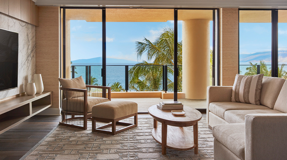 Living room of an oceanfront suite with floor-to-ceiling windows overlooking the water