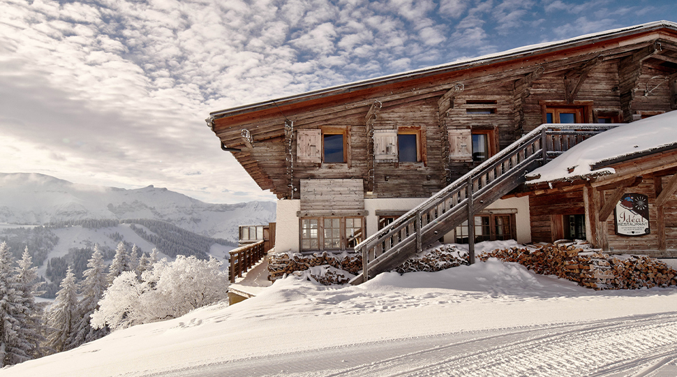 Alpine lodge surrounded by snow-covered terrain with mountains in the background