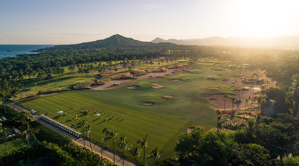 Aerial view of a tropical golf course with the sun setting in the distance