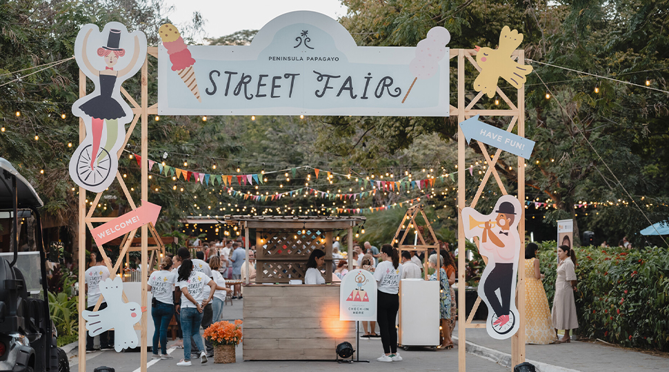 Entrance to a street fair with large cut outs, pennant garlands and string lights