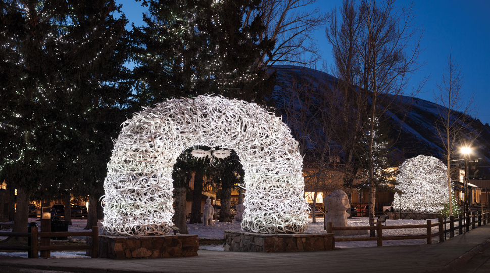 Archway made of antlers is illuminated by white lights at night