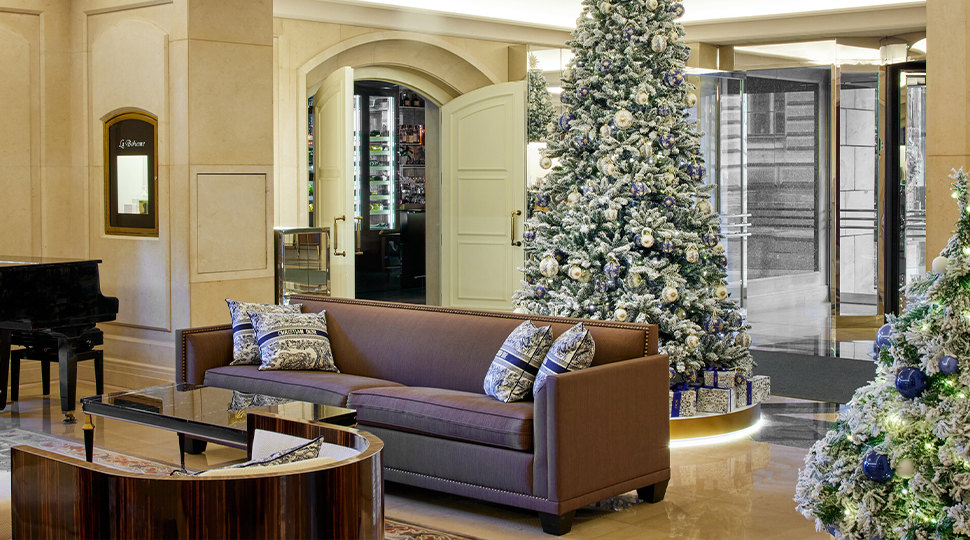 Hotel lobby with a sofa, coffee table, grand piano and two large Christmas trees