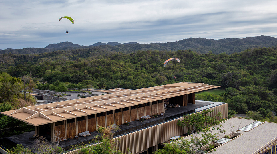 Two paratrikes glide over a resort building