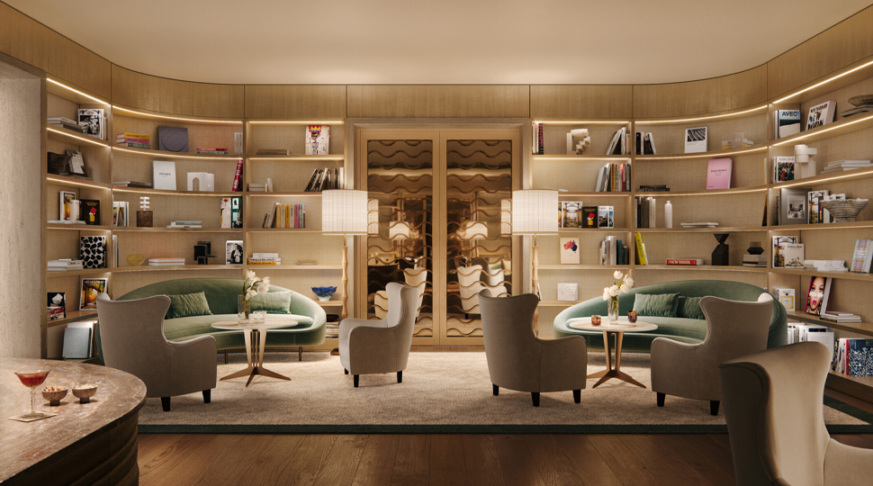 Intimate library with beige walls, light wood shelving along the walls, two sage green sofas and light-grey arm chairs